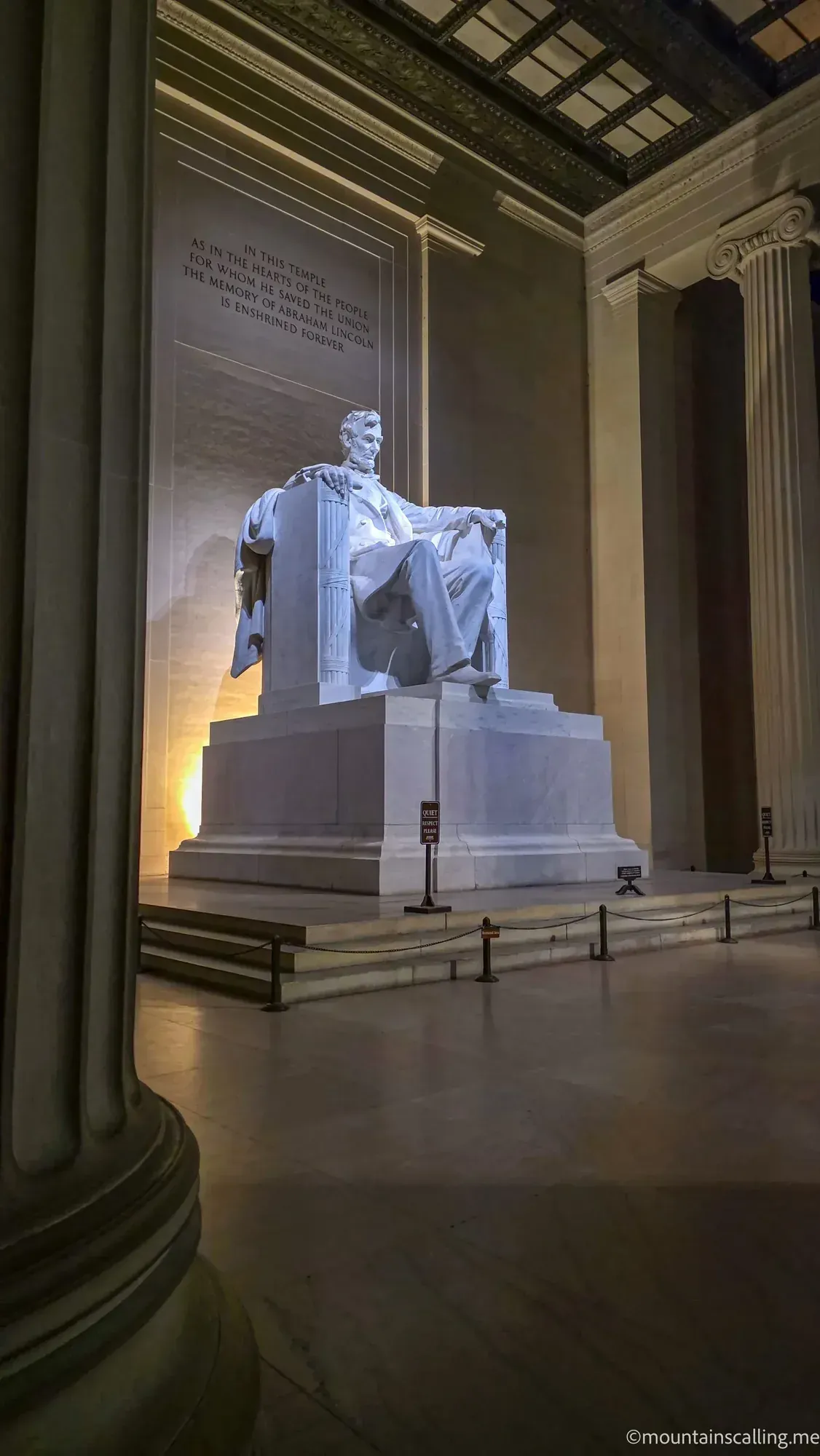 Lincoln Memorial statue illuminated at night, showing Abraham Lincoln seated with inscribed quote on marble wall