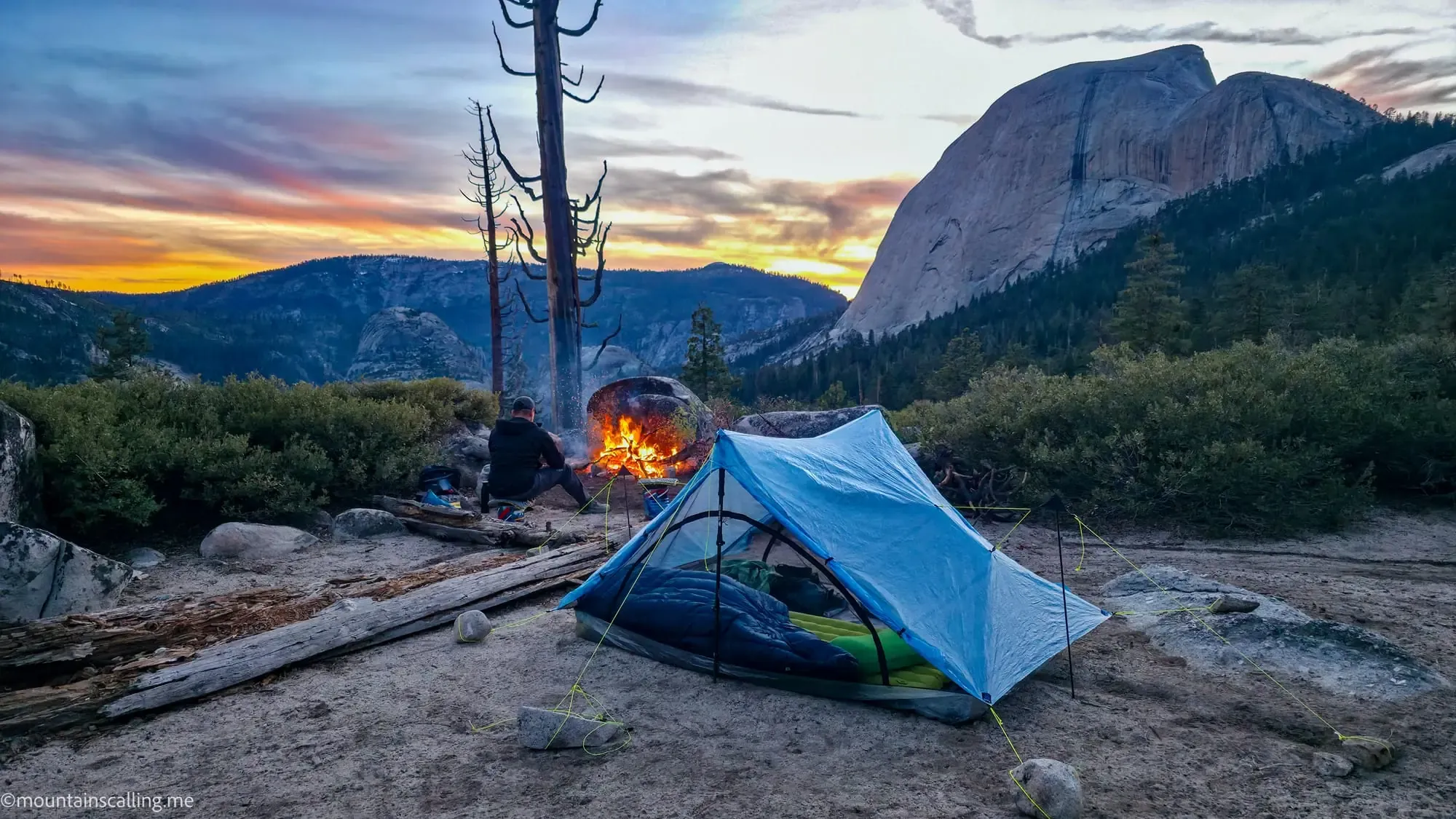Backcountry campsite with tent and campfire at sunset during Clouds Rest backpacking trip in Yosemite wilderness