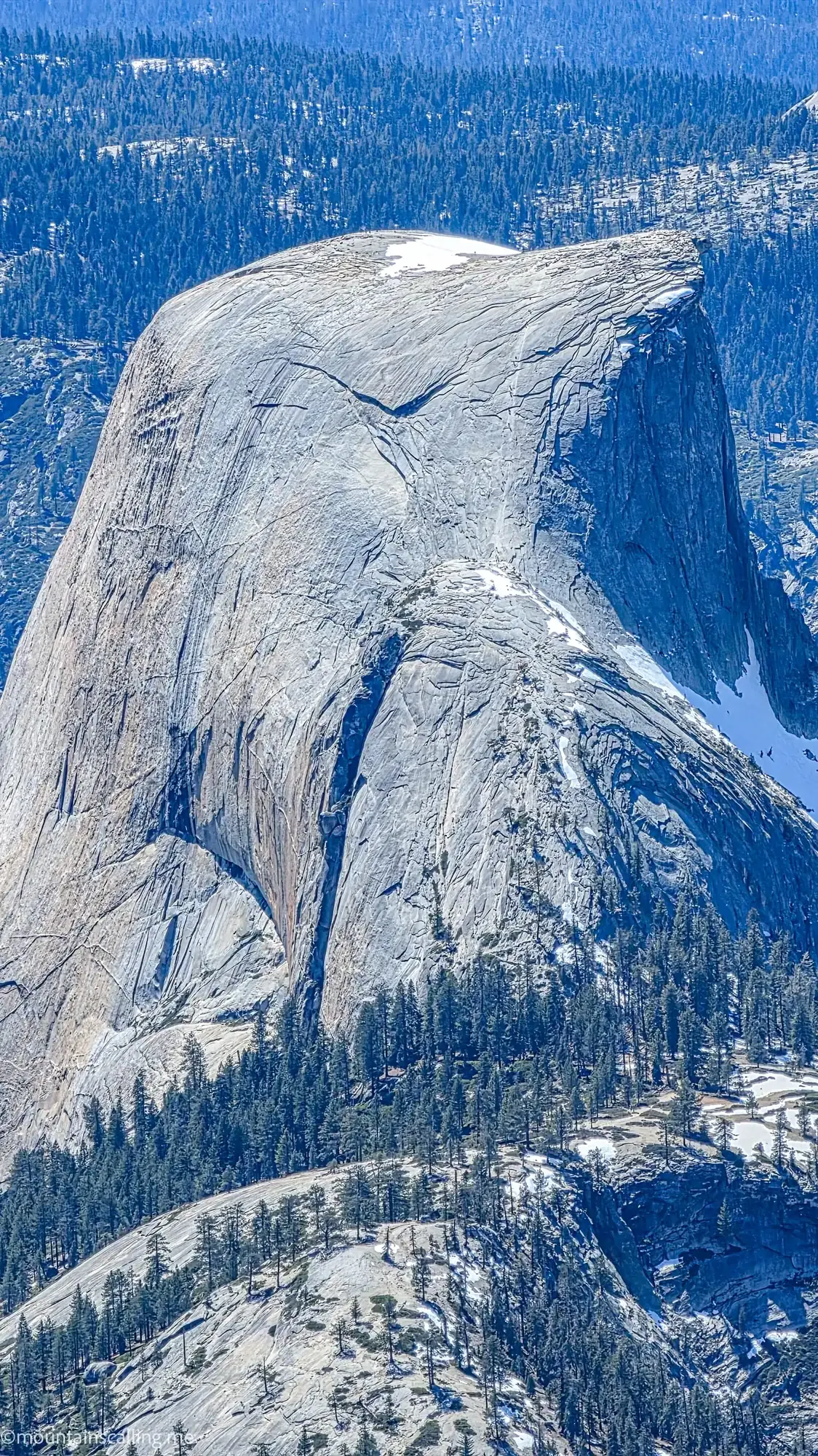 Half Dome northwest face showing granite cliff detail and snow patches from Clouds Rest wilderness area