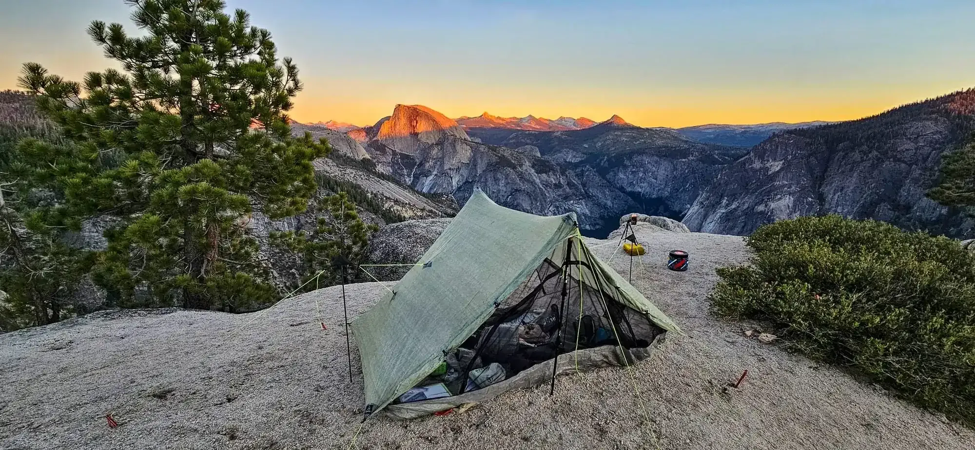 Ultralight tent pitched on granite ledge overlooking Half Dome at sunset during guided Yosemite backpacking trip