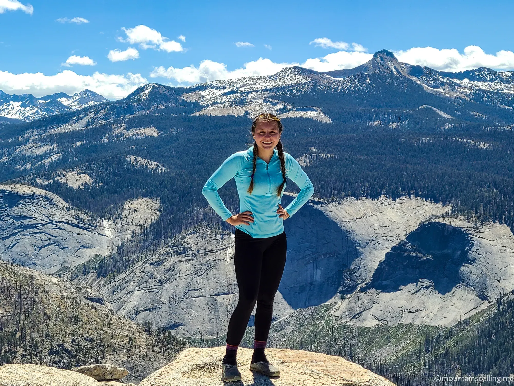 Smiling hiker on the Half Dome summit with High Sierra panorama behind her