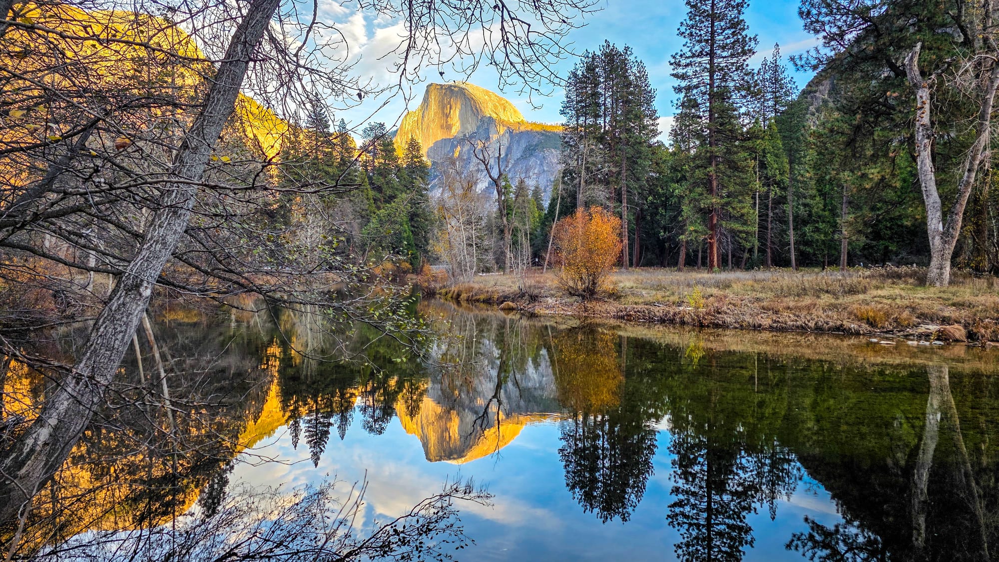Half Dome glowing and reflecting in the mirror-like Merced River.