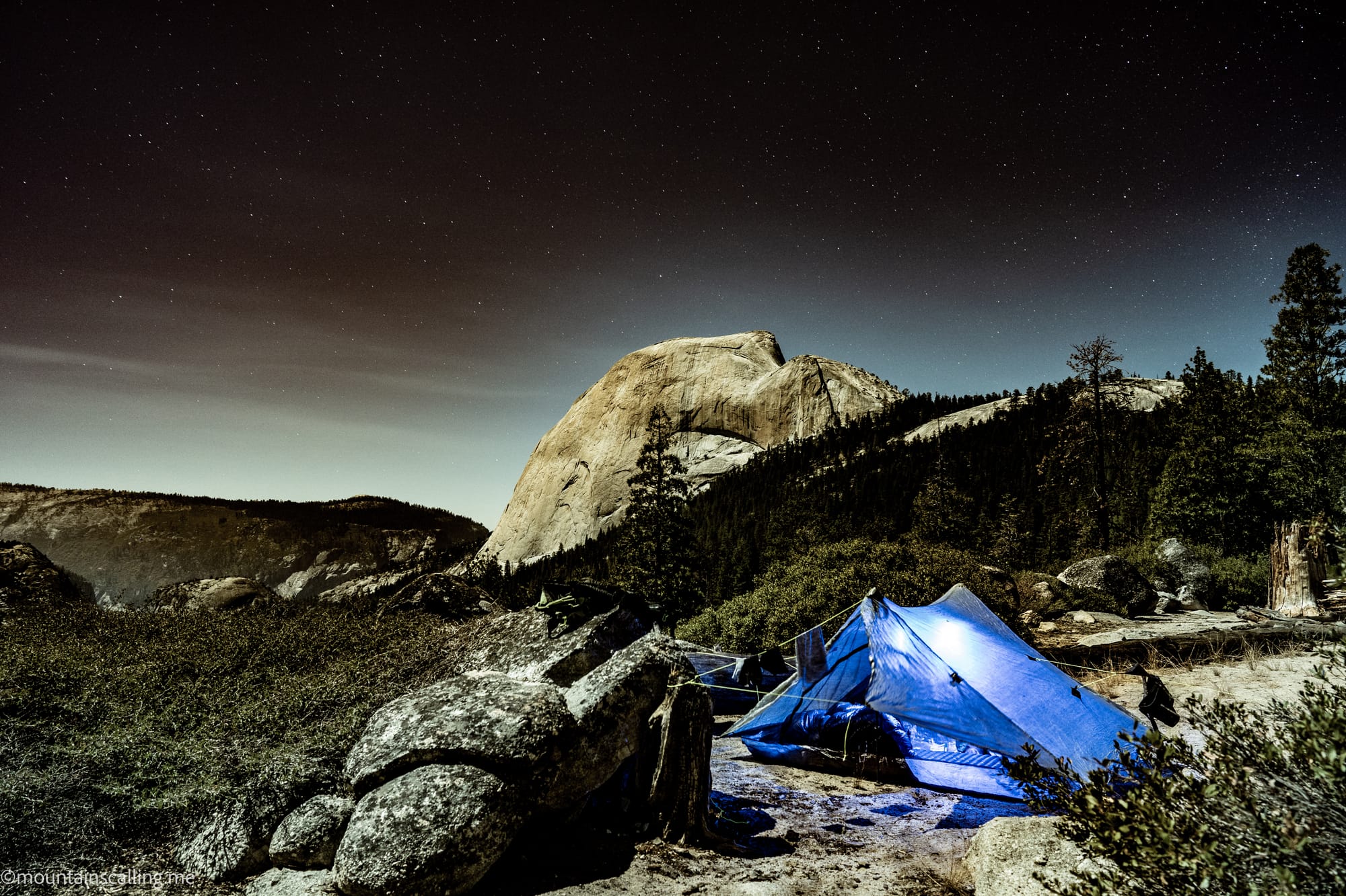 Stars over Half Dome with a blue tent lit up at a nearby campsite | Yosemite Life