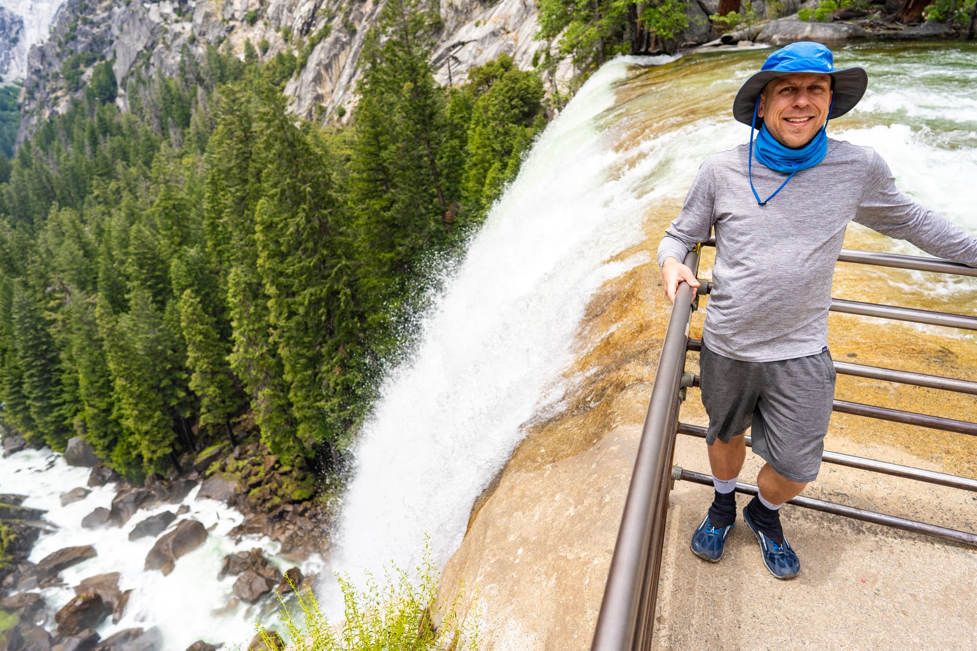 Eric Kufrin standing at the railing at the brink of Vernal Fall in Yosemite with the waterfall dropping 317 feet behind him | Yosemite Life | Yosemite.Life
