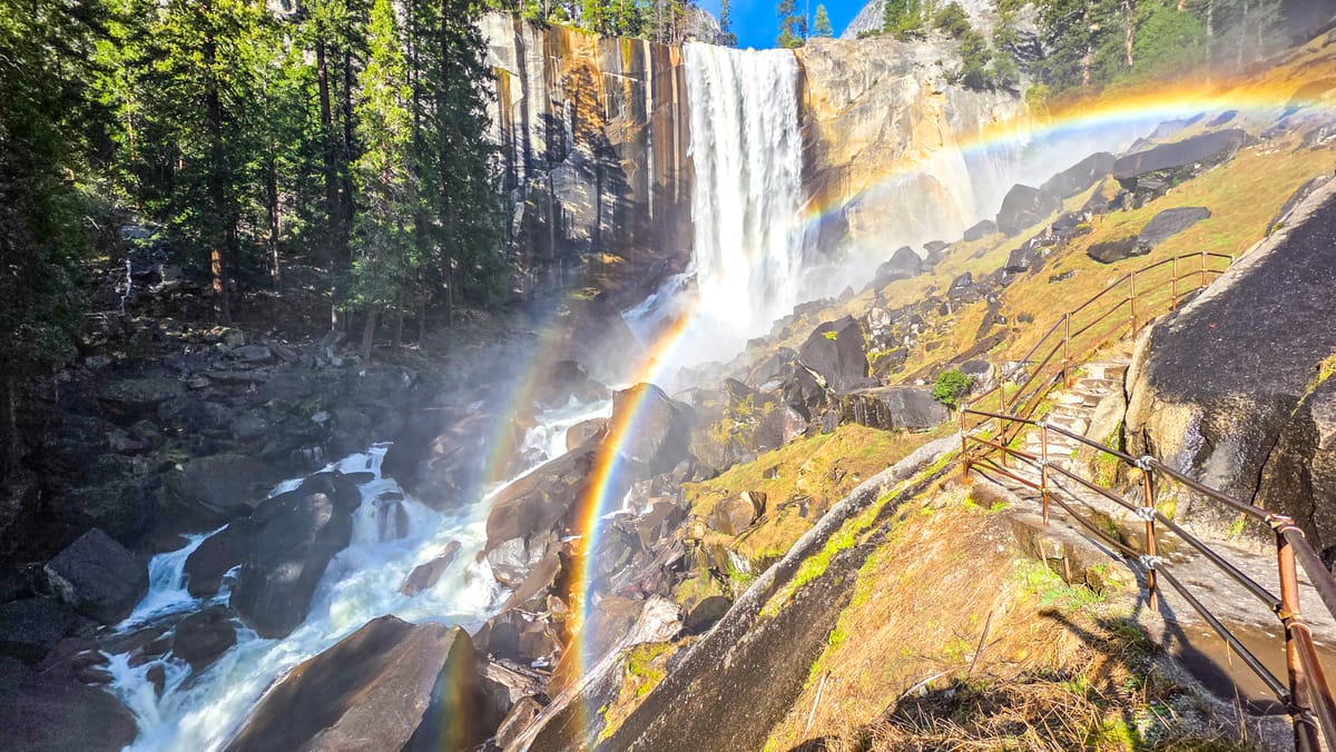 Double rainbow on the granite steps of the Mist Trail next to Vernal Fall in Yosemite National Park with metal railings and mist visible | Yosemite Life | Yosemite.Life